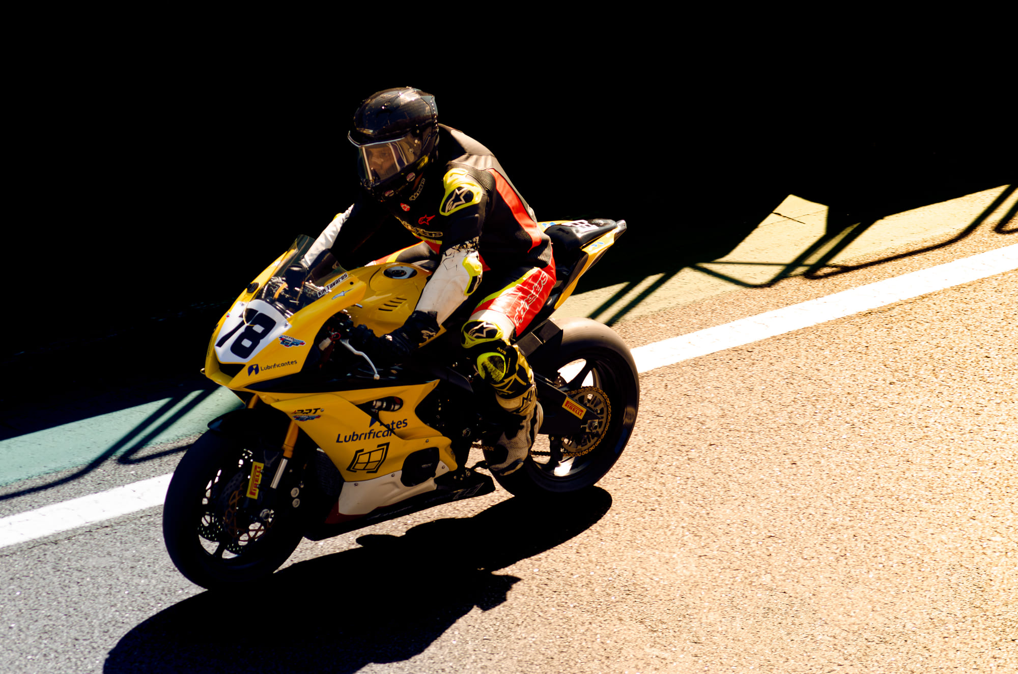 Moto amarela #78 da Ipiranga Lubrificantes, da classe GP600, pilotada por Kik Tavares, saindo da sombra para a luz, recortada contra a zebra no pit lane na Moto1000GP 2026 - Etapa 5, Interlagos