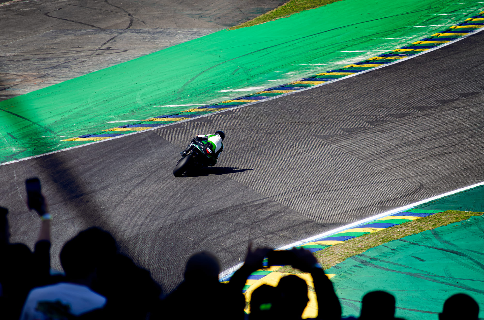 Moto #55 da Castrol, da classe GP1000, pilotada por Mauro Passarino, vista de cima na reta, com o público em silhueta filmando em primeiro plano no Moto1000GP 2026 - Etapa 5, em Interlagos