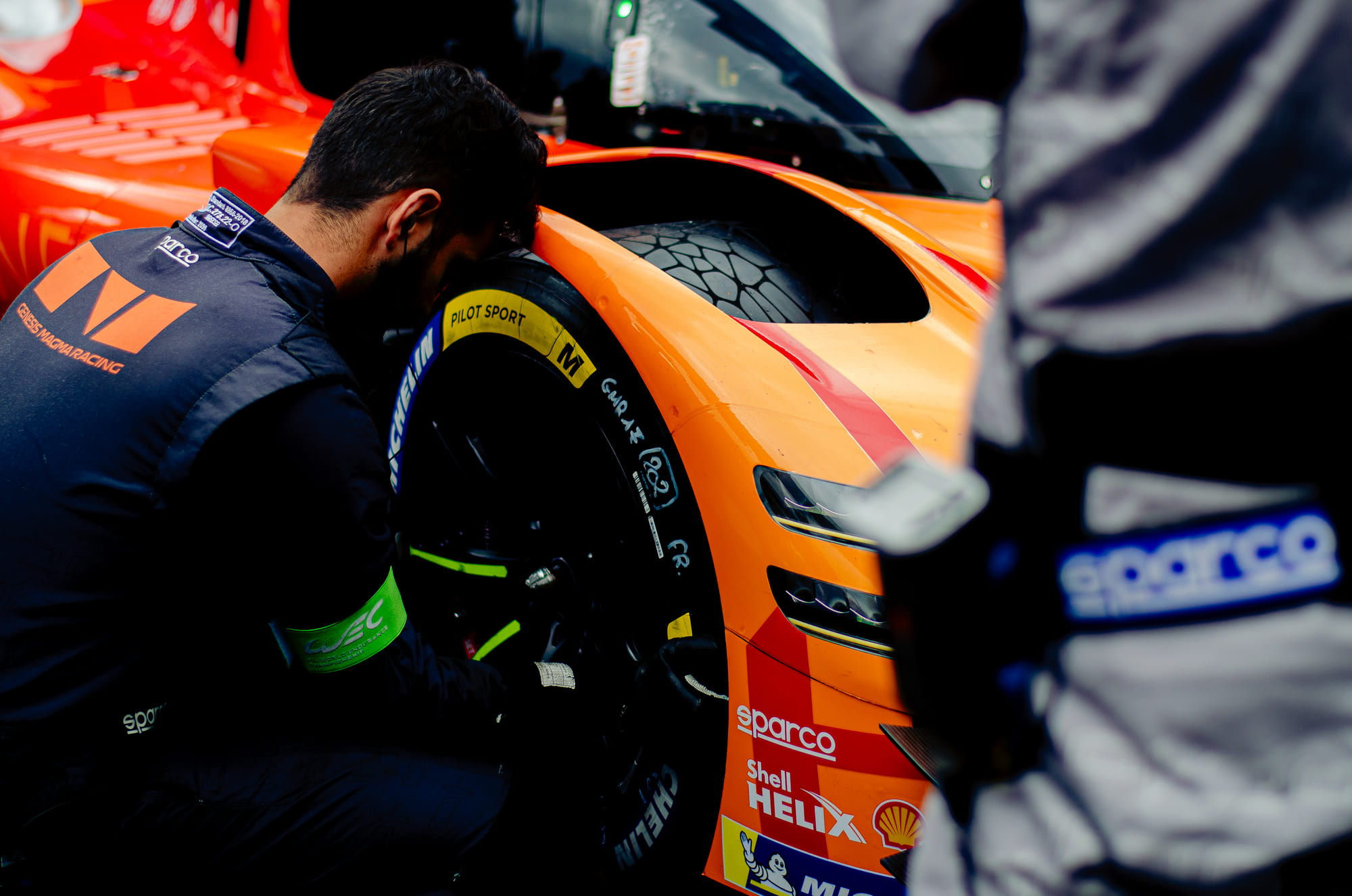 Mecânico da Genesis Magma Racing agachado na roda dianteira do carro laranja #17, da classe Hypercar, durante o grid walk no WEC 6 Horas de São Paulo 2026, em Interlagos